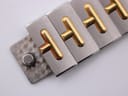 Close-up of the bracelet clasp detail, showing the gold-plated 'T' links and folding mechanism.
