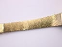 Detailed close-up of the textured gold-tone mesh bracelet design.