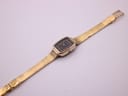 Full length, angled view of the Tissot gold-tone watch with its mesh bracelet extended.