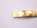 Close-up of the gold-tone folding clasp on the mesh bracelet, showing the engraved Tissot 'T' logo.
