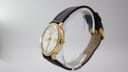 Top-down view of the Mondaine watch with its black leather strap extended, set against a plain background.
