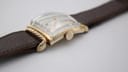 Full view of the watch from the case back perspective, showing the brown leather strap extended.