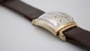 Side view of the watch on a clear display stand, emphasizing the curved profile.