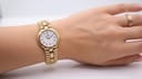 Raymond Weil gold-plated watch worn on a female wrist, showcasing its size and elegance.