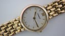 Close-up front view of gold tone Tissot 329-S325 dial with white face, gold baton indices, and Roman numeral at 12.