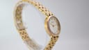 Another angled side view of the Tissot 329-S325 watch, showing the crown and the curve of the integrated gold tone bracelet.