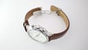 Overhead view of the Tissot watch and brown leather strap with the butterfly deployant clasp open.