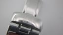 Close-up of the polished stainless steel Tissot signed butterfly deployant clasp on the brown leather strap.