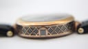 Macro shot of the Gucci watch case side, detailing the intricate black and rose gold pattern and crown.