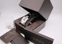 Close-up of the rectangular black dial and brushed steel integrated bracelet of the Gucci watch.