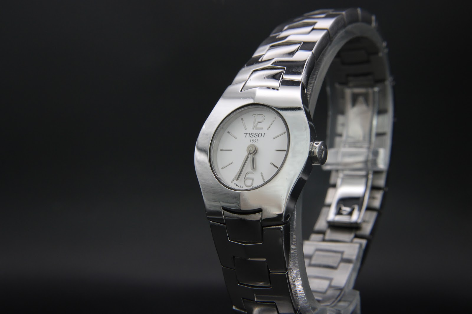 Front-angled view of the Tissot L520 watch on a black stand, emphasising the sleek case and dial with 6 and 12 numerals.