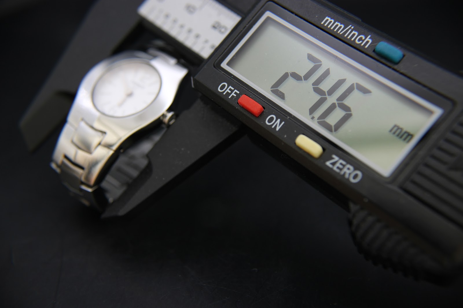 Digital caliper measuring the watch case diameter, displaying 24.6 mm.