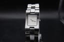 Front-face view of the Gucci 2305L watch, showing the minimalist silver square dial with "GUCCI" logo and simple baton hands, on a display stand.