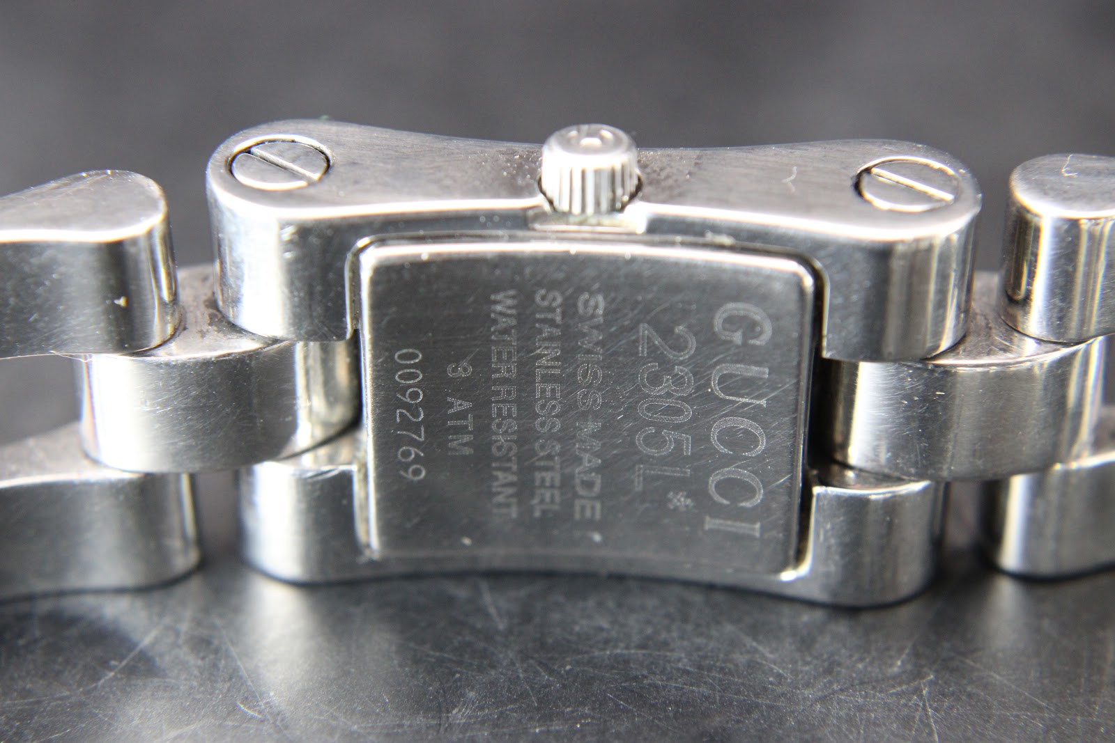 Close-up of the engraved case back of the Gucci 2305L watch, showing "GUCCI", "2305L", "SWISS MADE", "STAINLESS STEEL", "WATER RESISTANT 3 ATM", and serial number "0092769".