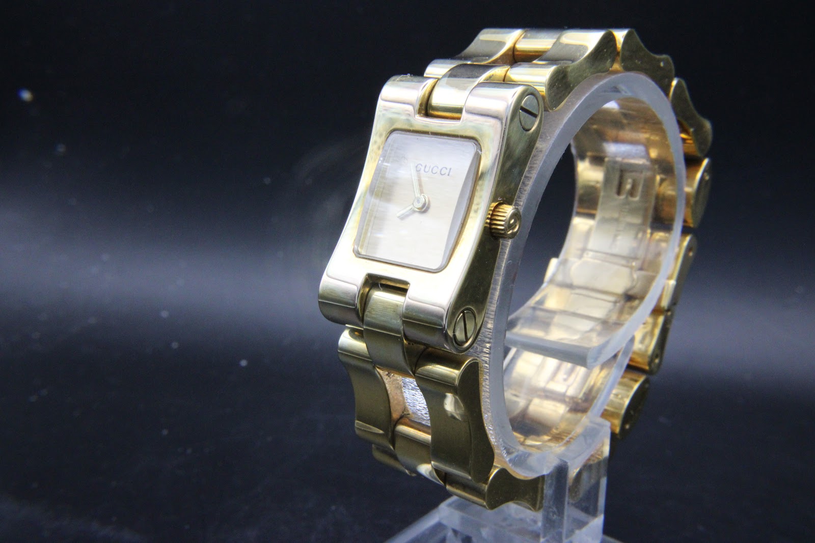 Front-right view of Gucci 2305L showing the slim rectangular case, fluted crown, and surface scratches on the mineral crystal.