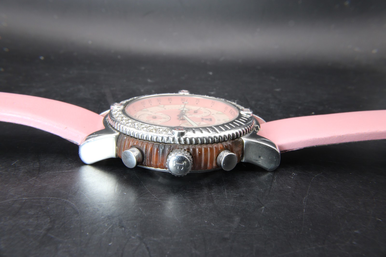 Side view of the watch case, highlighting the ridged brown mid-case, screw-down crown with 'F' logo, and chronograph pushers.