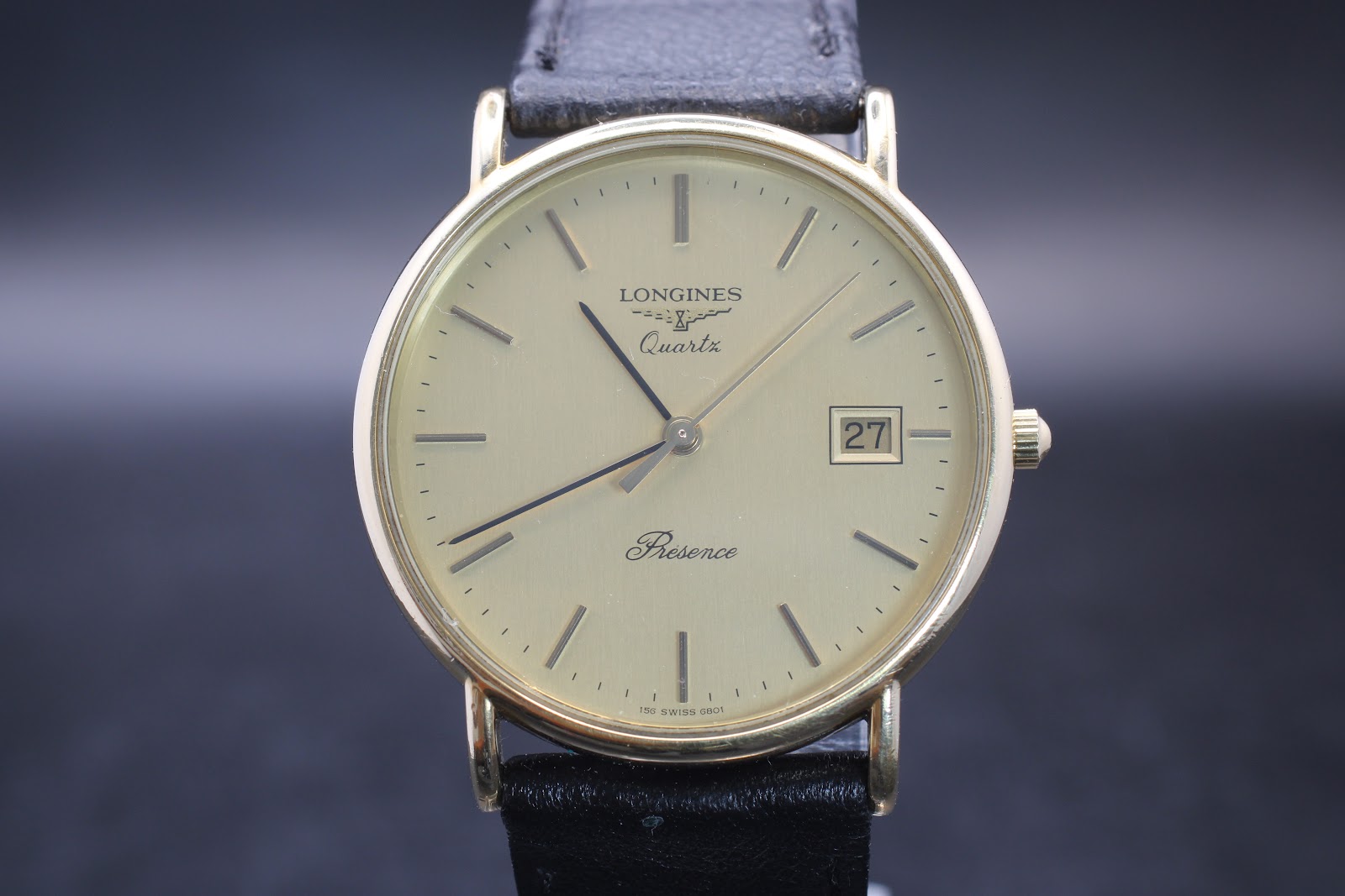 Front view of the Longines Présence watch dial, featuring a champagne face, baton indices, and a date window at 3 o’clock.