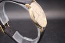 Another side profile view of the watch on a display stand, showing the case lugs and part of the black leather strap.