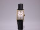 Front view of the gold plated Omega Geneve watch with white rectangular dial and black leather strap.