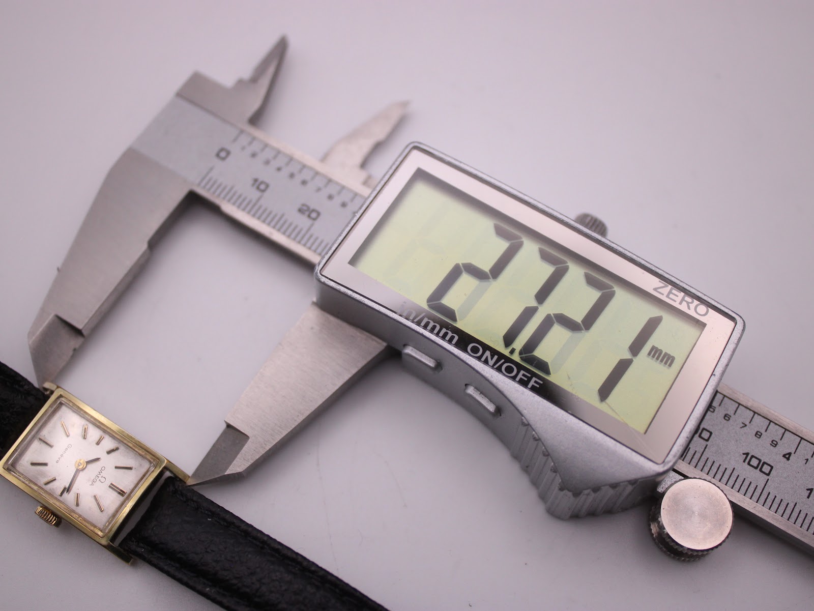 Digital caliper measuring the length of the Omega Geneve watch case at 27.21 mm.