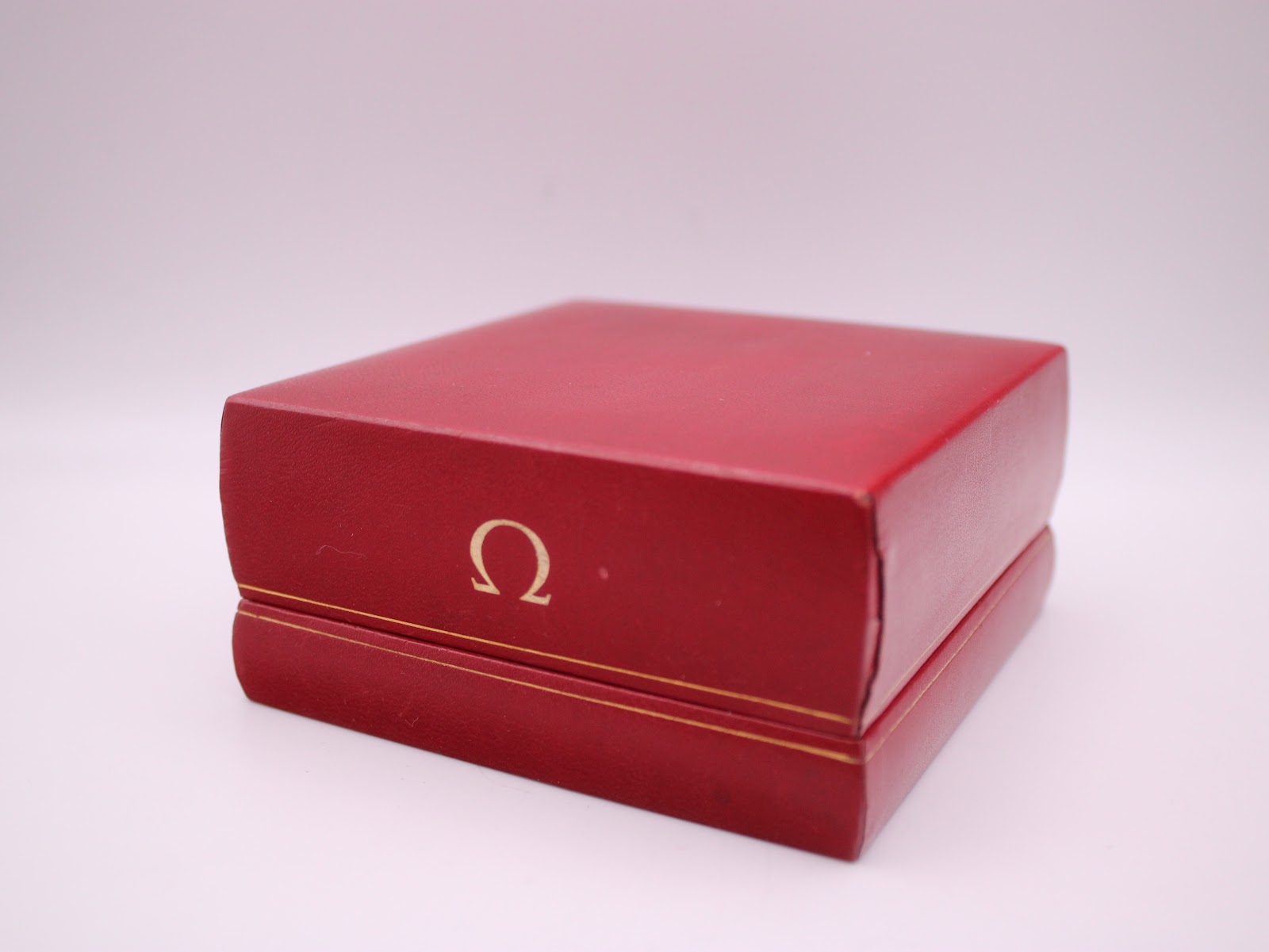 Closed view of the vintage red Omega presentation box with gold Omega logo.