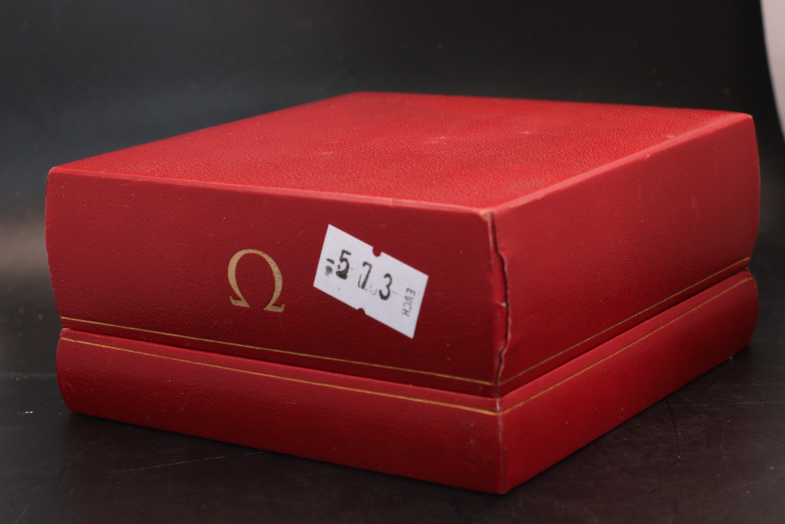 Exterior view of the closed red original Omega presentation box, showing the embossed Omega logo and gold trim.