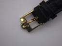 Close-up of the gold-toned pin buckle on the black leather strap, featuring the Omega logo.