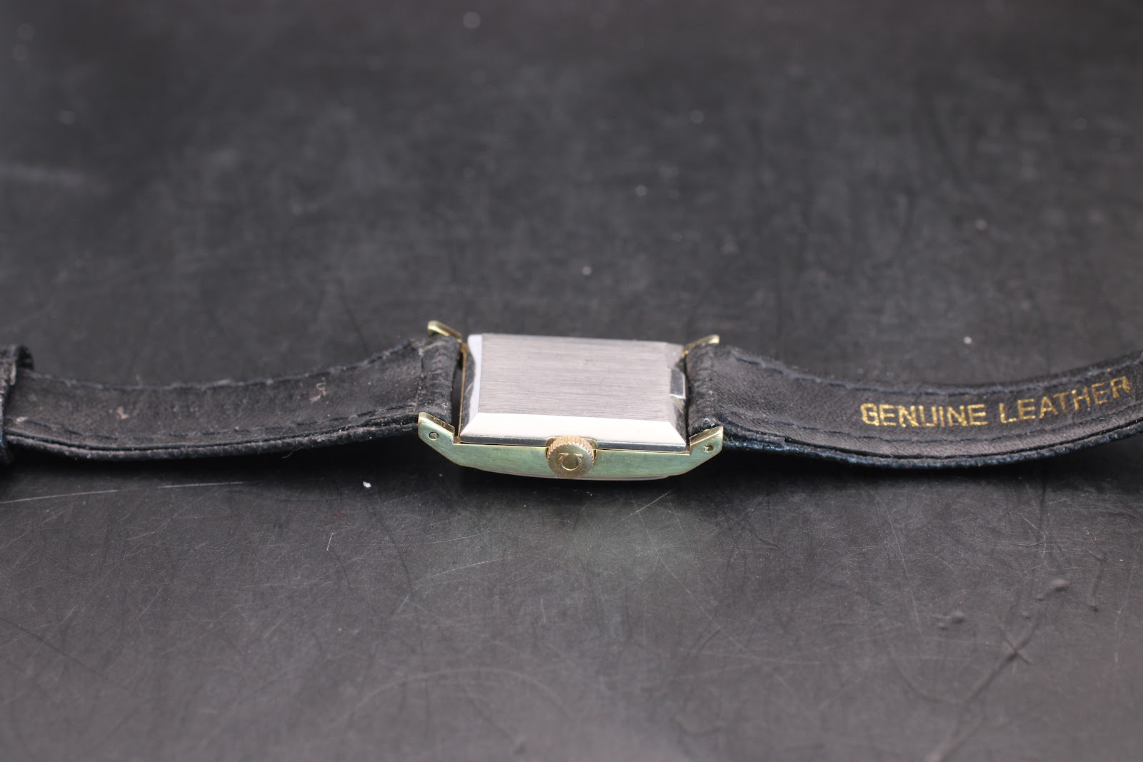Rear view of the Omega Genève watch, showing the brushed stainless steel case back and black leather strap.
