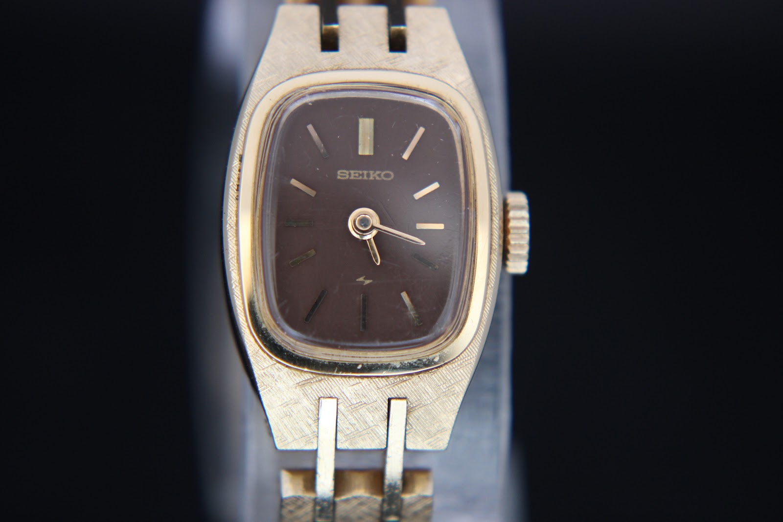 Front view of gold-tone Seiko 11-3520 watch, showing rectangular brown dial with gold baton indices.