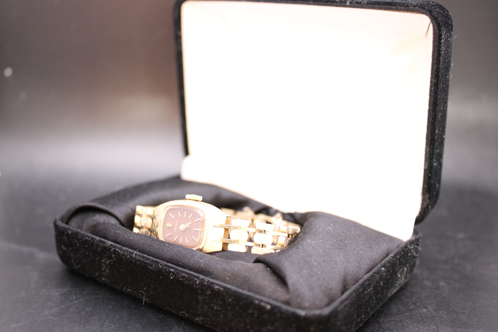 The gold-tone Seiko watch resting in an open black velvet watch box.
