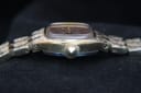 Angled side view of the watch crown, showing minor wear on the gold-tone case.