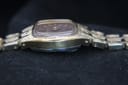 Left side view of the watch case, showing the textured gold-tone finish and slim profile.
