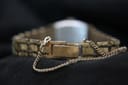 Close-up of the integrated gold-tone bracelet clasp with a safety chain, showing textured links.