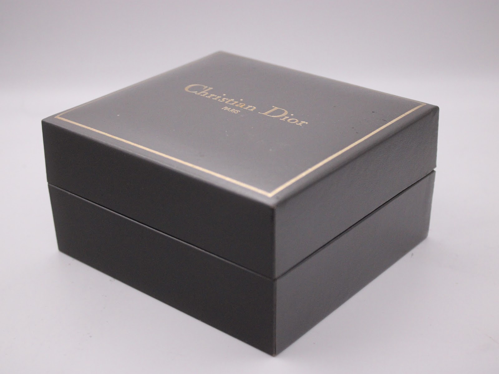 Exterior view of the closed original Christian Dior watch box in black with gold lettering and trim.