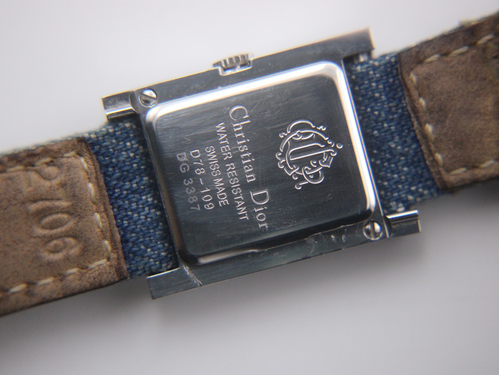 Close-up of the watch case back, revealing 'Christian Dior', 'WATER RESISTANT', 'SWISS MADE', model 'D78-109', and serial 'DG3387' engravings, with strap lining visible.