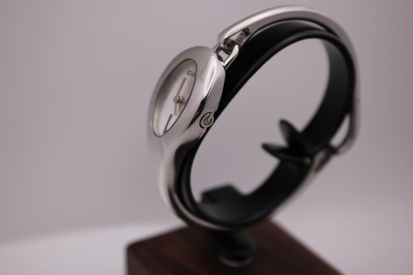 Side view of the Gucci 103 watch on a stand, highlighting the curved bangle and crown with 'G' logo.