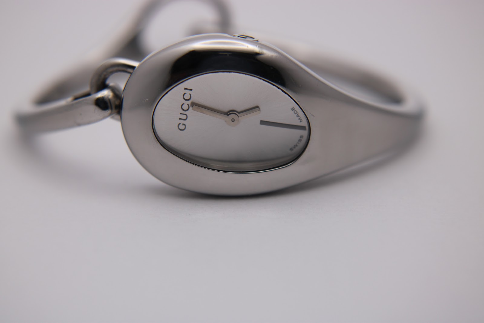 Close-up, low-angle front view of the Gucci 103 watch dial, showing 'GUCCI' text and 'SWISS MADE' at 6 o'clock.