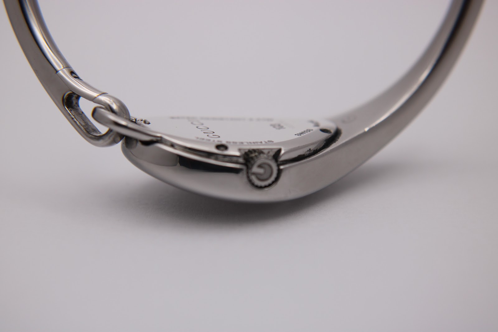 Close-up of the watch's right side, showing the crown with a 'G' logo and the integrated case and bangle design.