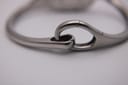 Close-up of the articulated hinge mechanism of the stainless steel bangle bracelet.