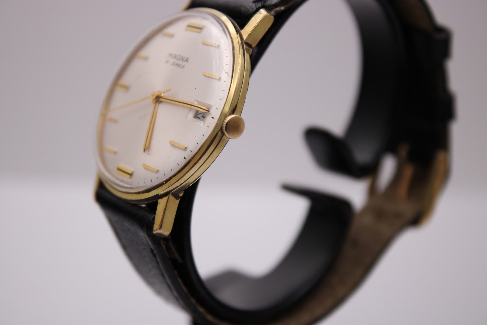 Side view of the Magna 21 jewels watch, showing the crown and the curvature of the gold-tone case.