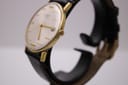 Side view of the Magna 21 jewels watch, showing the crown and the curvature of the gold-tone case.