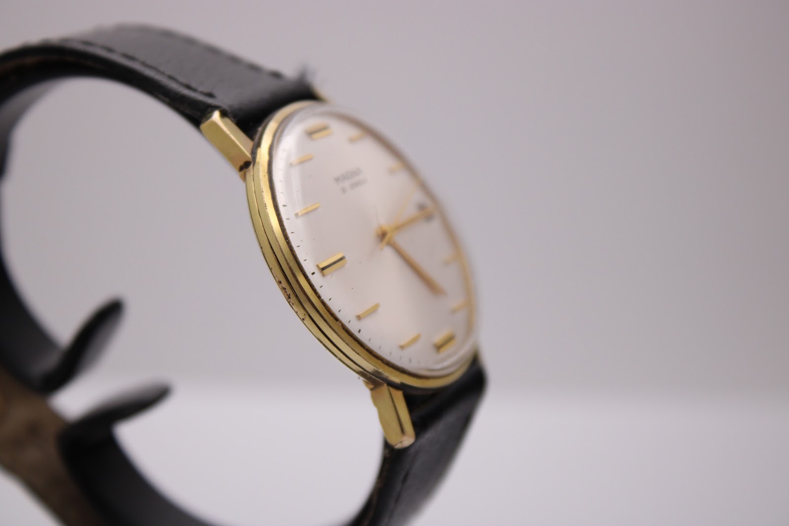 Close-up of the watch case from an angle, illustrating the vintage gold-tone finish and the profile of the crystal.