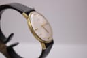 Close-up of the watch case from an angle, illustrating the vintage gold-tone finish and the profile of the crystal.