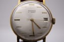 Close-up, face-on view of the Magna 21 Jewels silver dial, showing gold baton indices, three gold hands, and a date window displaying '19'.