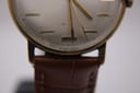 Extreme close-up of the lower part of the Magna watch dial, revealing 'SWISS MADE' text and the connection point of the brown leather strap.