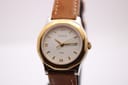 Front view of the Tissot PRX P340-G on a dark watch stand, highlighting the white textured dial with gold-tone Roman numerals.
