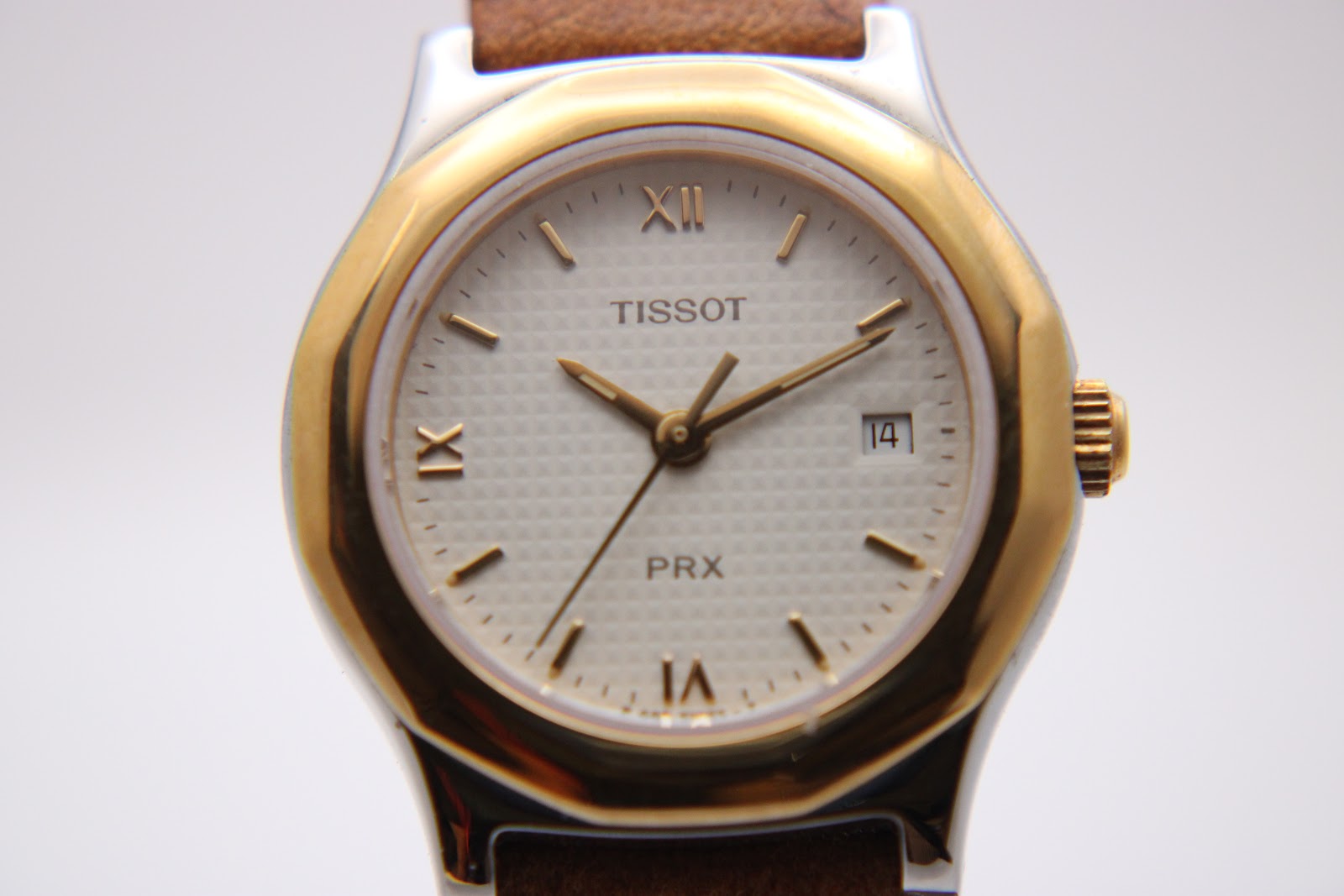 Close-up front view of the Tissot PRX P340-G dial, showing the intricate texture, gold hands, and date window at 3 o'clock.