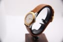 Right-side profile view of the Tissot PRX P340-G on a stand, focusing on the gold-tone crown and case side.