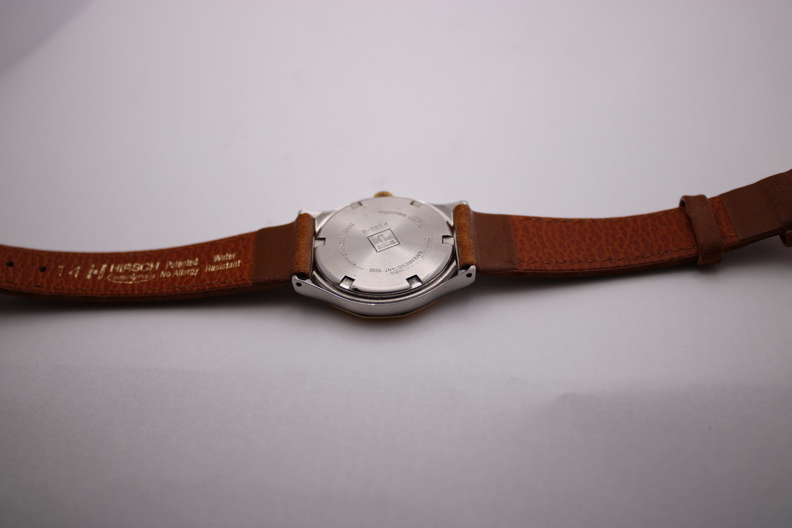 Overhead view of the Tissot PRX P340-G from the case back, displaying the full brown leather strap and stainless steel case back.