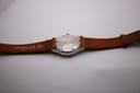 Overhead view of the Tissot PRX P340-G from the case back, displaying the full brown leather strap and stainless steel case back.